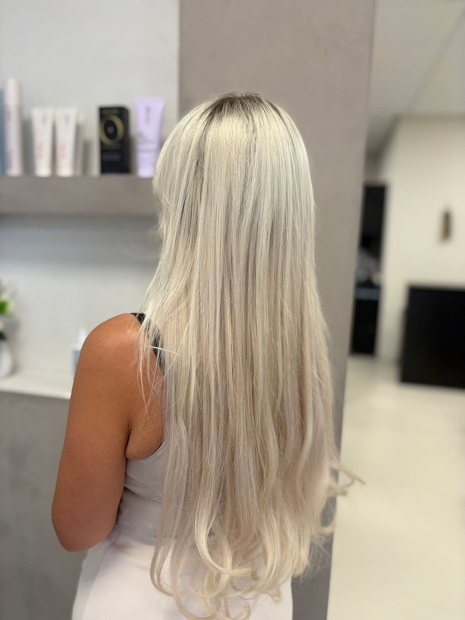 Lang, steil platinablond haar, van achteren gezien in de salon.