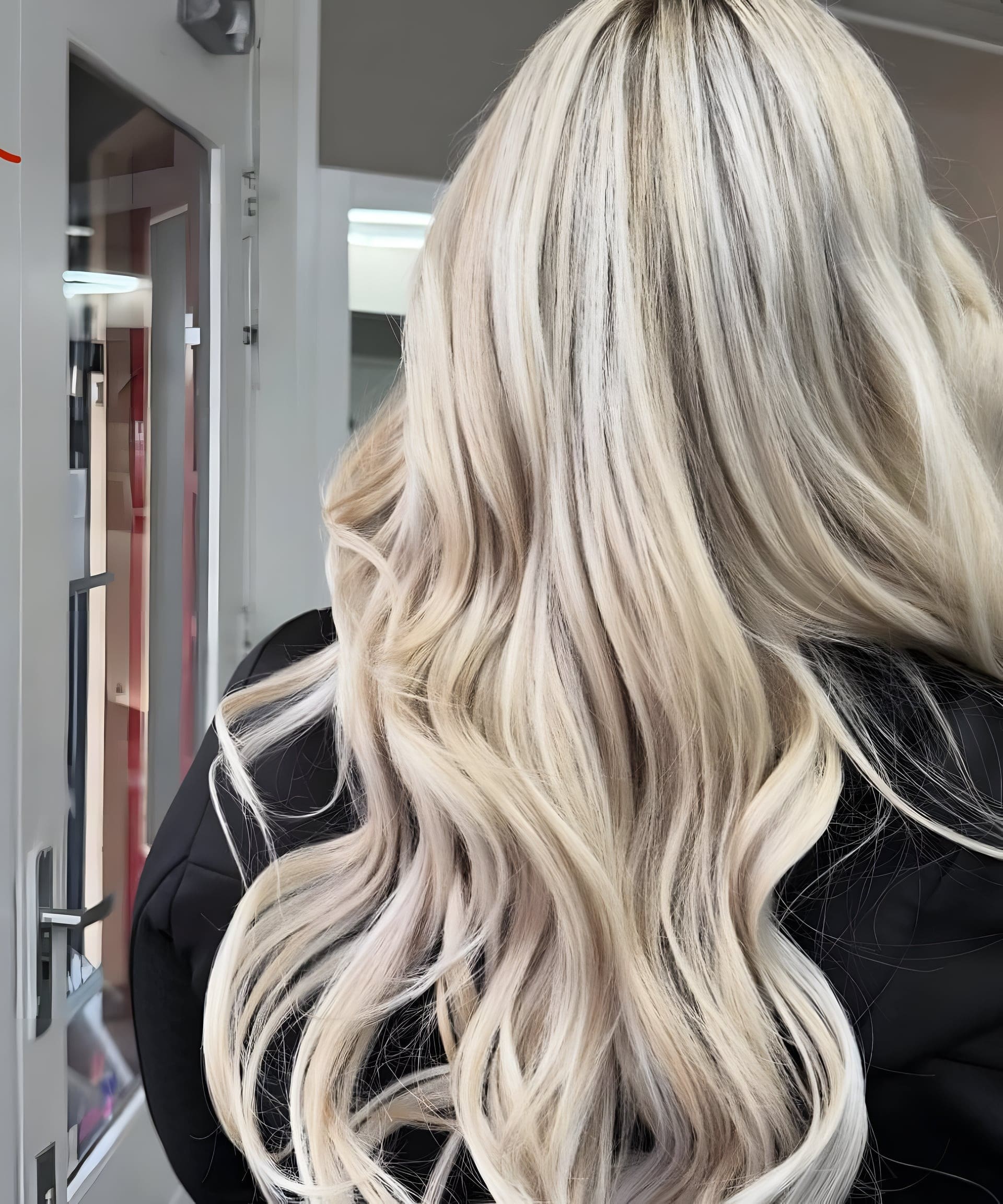 Lang blond haar met zachte golven en lichte highlights, van achteren gezien.